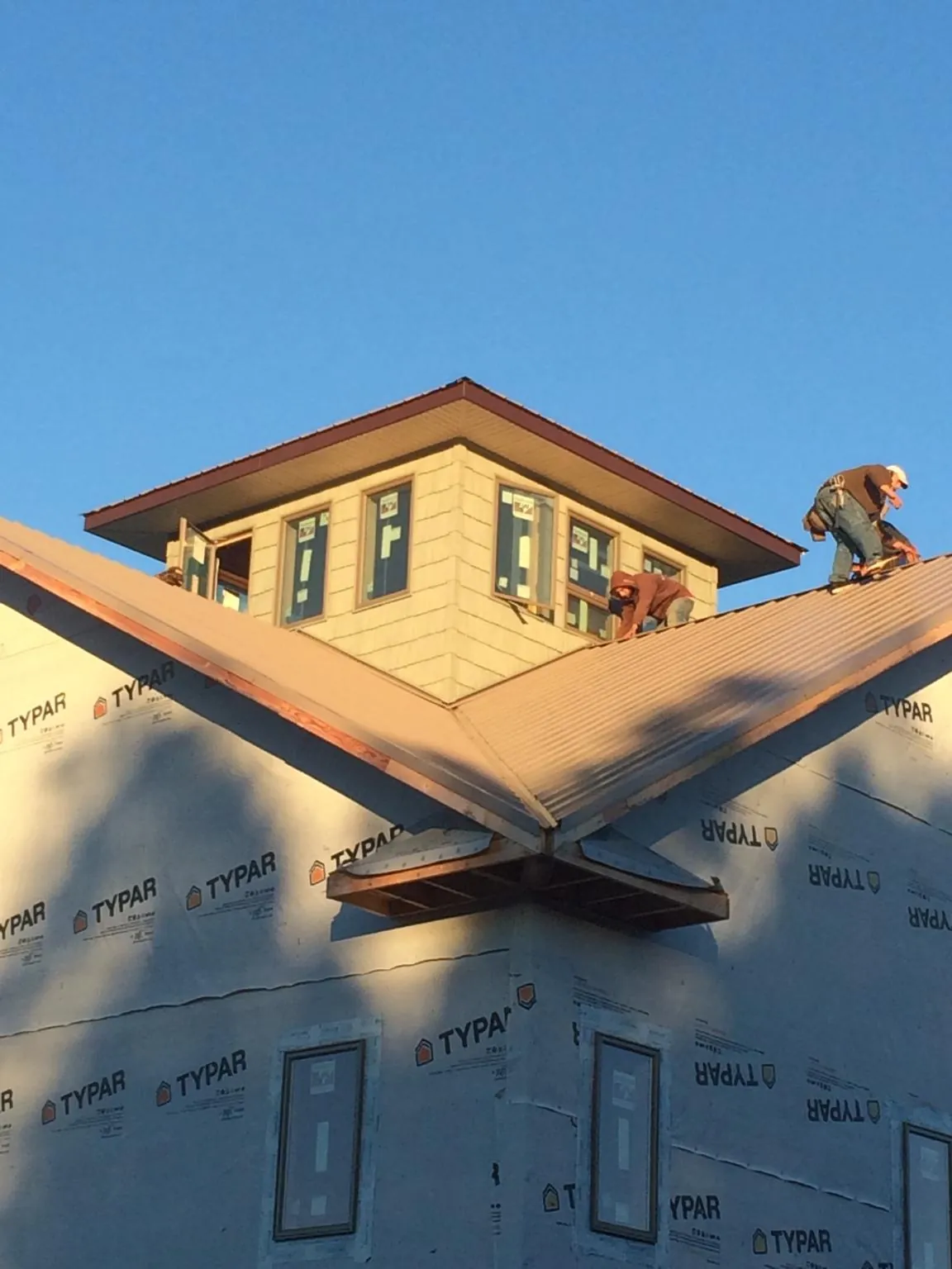 Roofers working around a rooftop cupola on a new metal roof at sunset — Roof Waterproofing in Clinton by Roofing Brothers